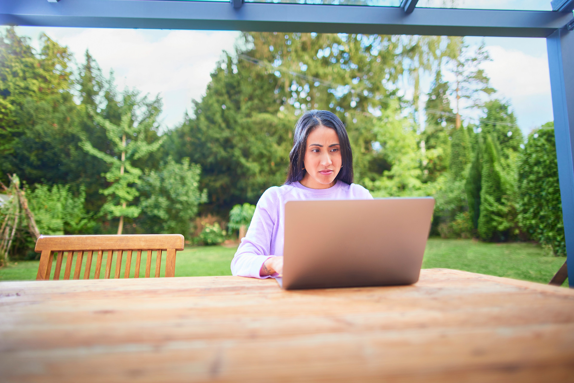 Frau am Laptop bearbeitet Ihren Tarif Eine Frau sitzt mit einem Laptop im Garten und informiert sich über die NEW Energie.
