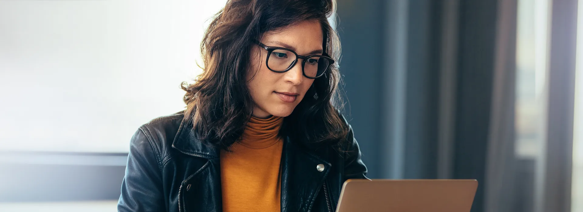 Frau macht sich mit NEW Energie vertraut Eine Frau mit schwarzer Brille sitzt am Tisch vor ihrem Laptop und schaut sich die NEW Energie an.