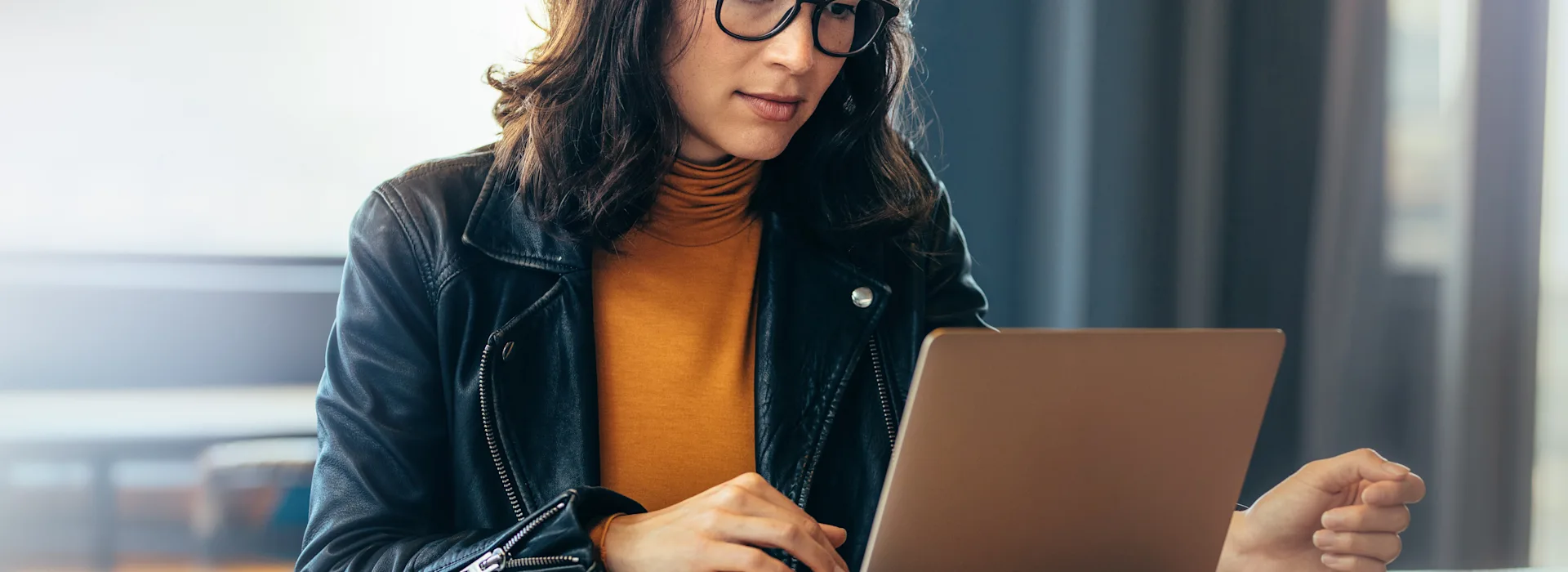 Frau macht sich mit NEW Energie vertraut Eine Frau mit schwarzer Brille sitzt am Tisch vor ihrem Laptop und schaut sich die NEW Energie an.