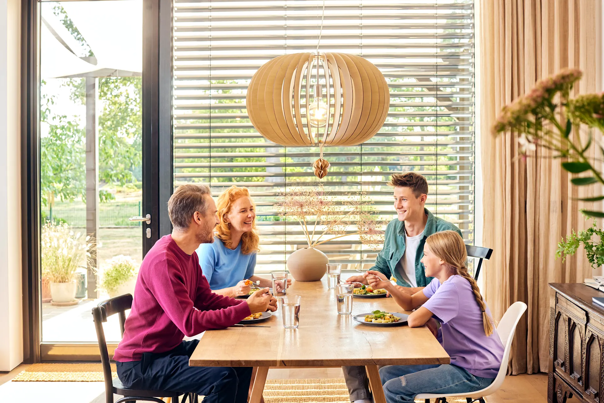 Eine Familie sitzt beim Essen an einem Esstisch und unterhält sich über günstiges Gas und günstigen Strom bei dem Stromanbieter NEW Energie.