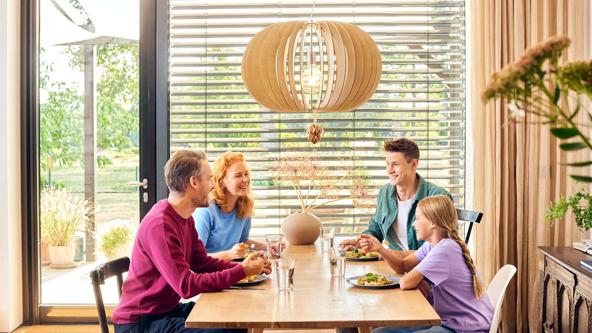 Familie beim Essen Eine Familie sitzt beim Essen an einem Esstisch und unterhält sich über günstige Tarife bei dem Stromanbieter NEW Energie.