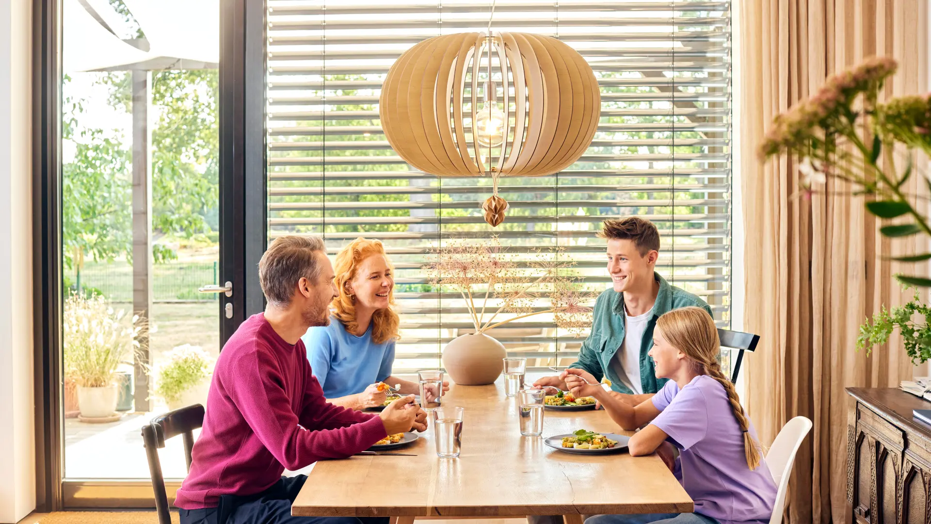 Eine Familie sitzt beim Essen an einem Esstisch und unterhält sich über günstiges Gas und günstigen Strom bei dem Stromanbieter NEW Energie.