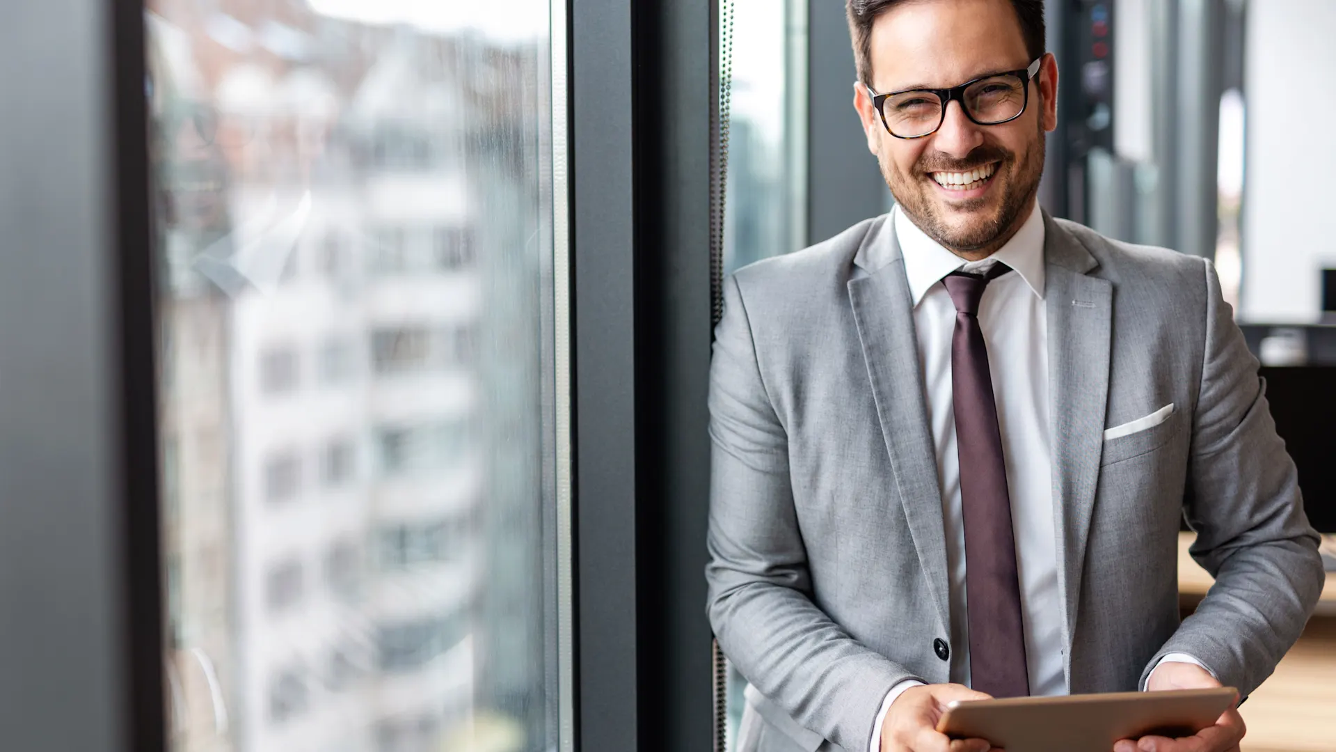 Mann mit Tablet informiert sich über den Service Ein Geschäftsmann steht mit einem Tablet in der Hand im Büro und informiert sich über den Service der NEW Energie.