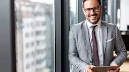 Mann mit Tablet informiert sich über den Service Ein Geschäftsmann steht mit einem Tablet in der Hand im Büro und informiert sich über den Service der NEW Energie.