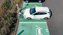 Leichtes E-Laden Eine Frau lädt mit einem Kind auf dem Arm das E-Auto auf dem Parkplatz von Borussia Mönchengladbach.