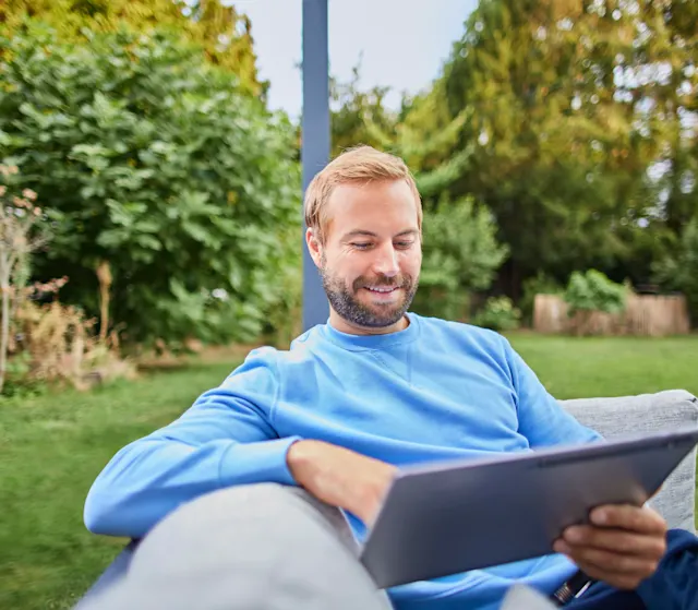Ein Mann informiert sich über Stromtarife Ein Mann sitzt im Garten und informiert sich mit einem Tablet über verschiedene Stromtarife der NEW Energie. Er möchte einen neuen Stromtarif abschließen.