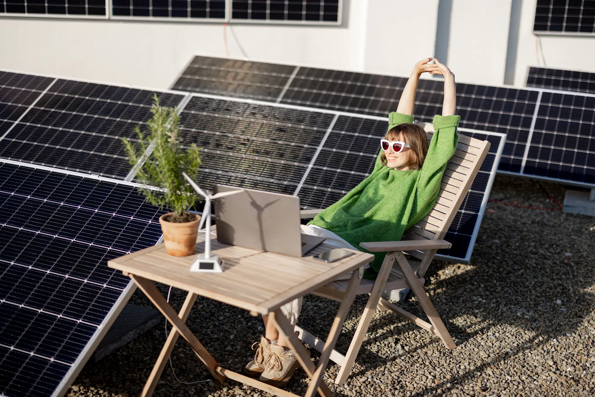 Die Frau sitzt neben einer Photovoltaikanlage auf dem Dach.