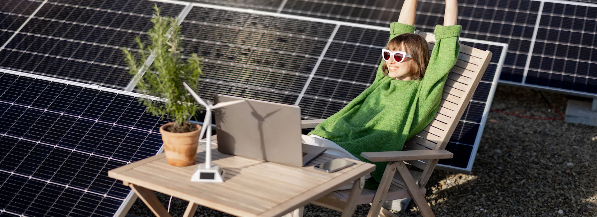 Strom selber erzeugen Die Frau sitzt neben einer Photovoltaikanlage der NEW Energie auf dem Dach.