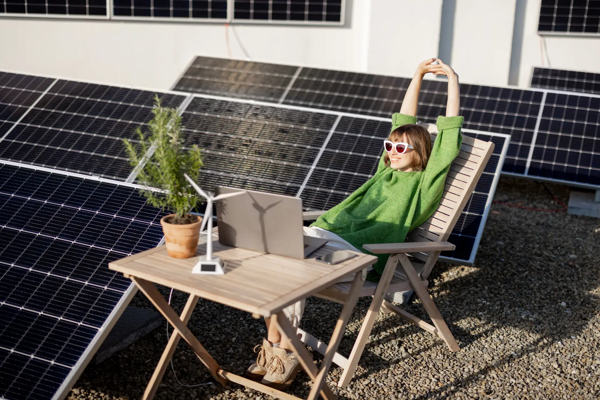 Die Frau sitzt neben einer Photovoltaikanlage auf dem Dach.