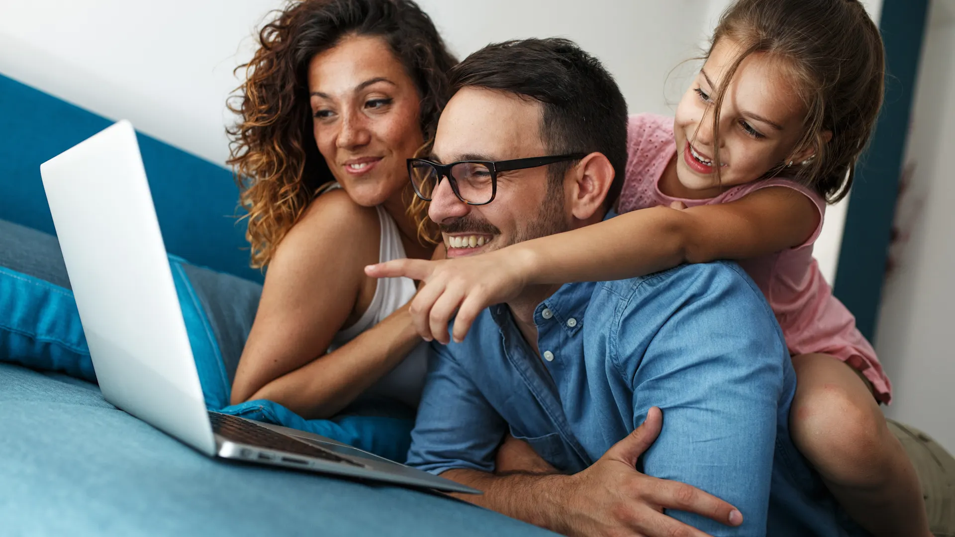 Günstige Tarife bei der NEW Energie Eine Familie sitzt zusammen auf dem Sofa und schaut sich die Tarife der NEW Energie an. Ein Mädchen zeigt aufgeregt auf den Laptop.