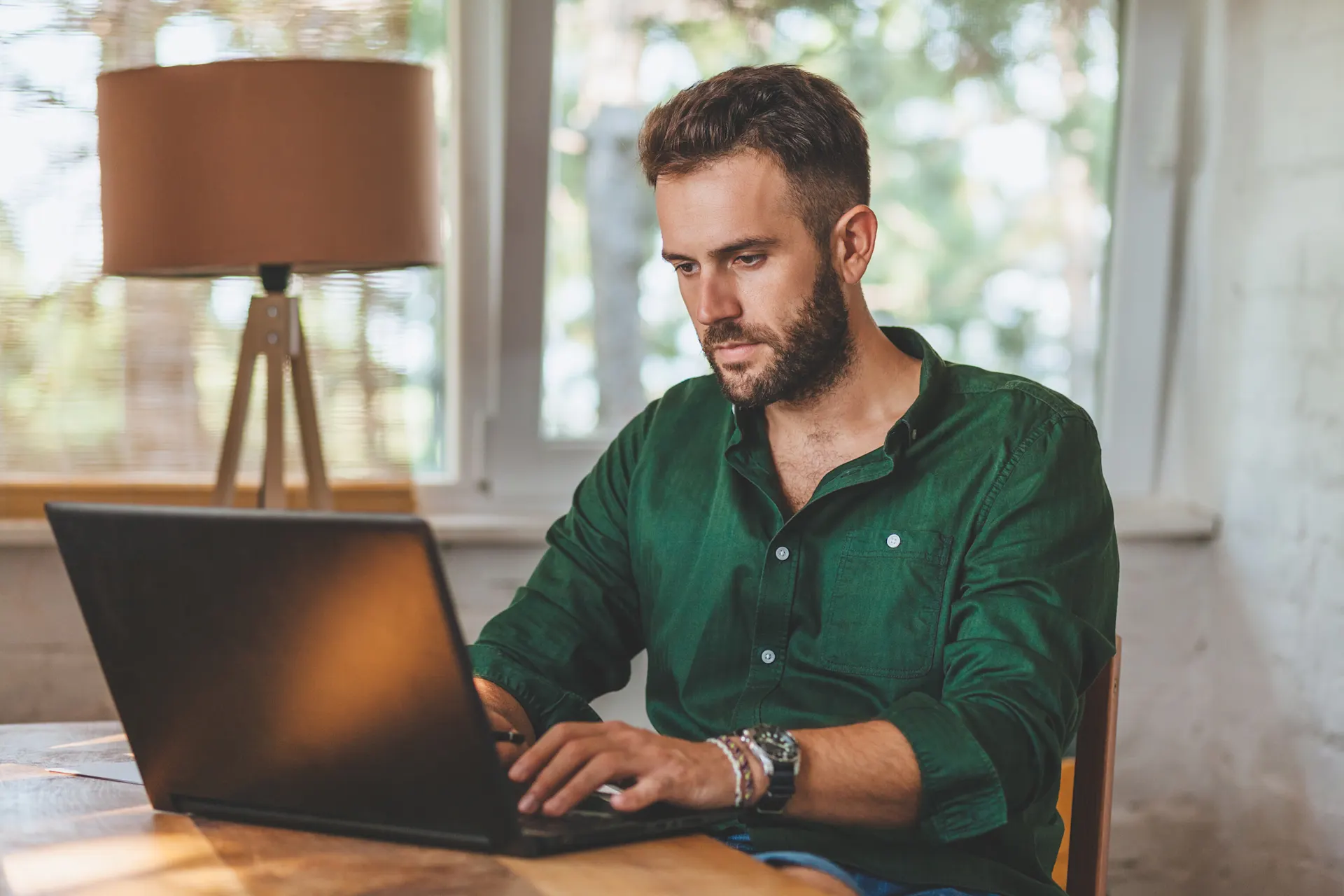 Ein Mann sitzt nachdenklich an einem Tisch vor seinem Laptop. Er vergleicht Tarife der NEW Energie.