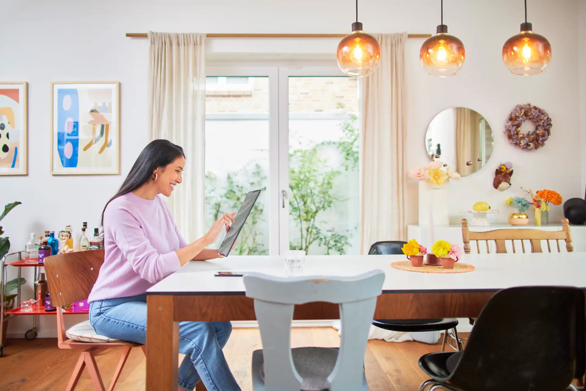 Eine Frau sitzt am Esstisch und schaut sich auf ihrem Tablet die Tarife des günstigen Energieversorgers NEW Energie an. 