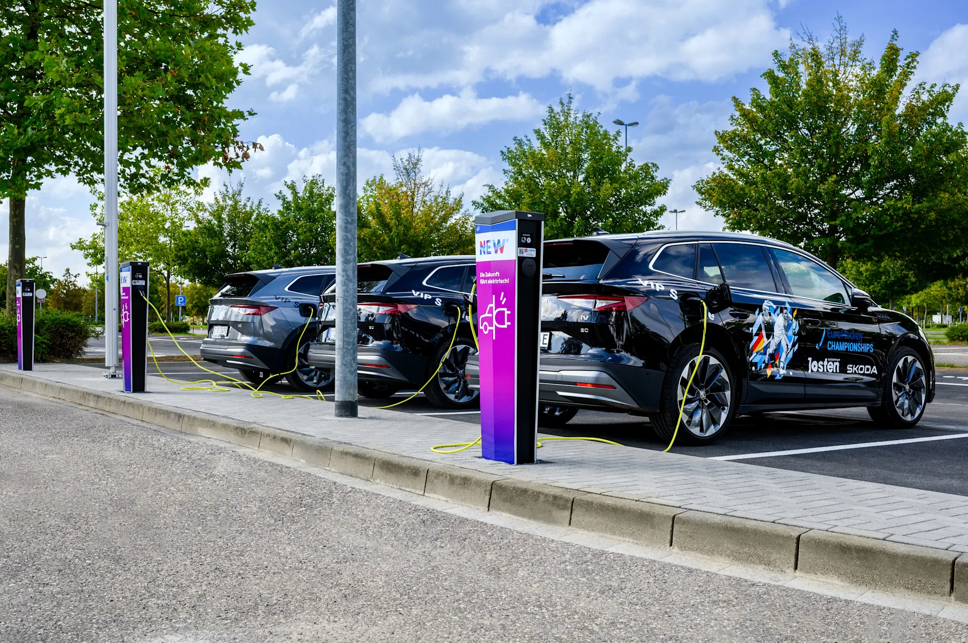 Drei E-Autos stehen an Ladesäulen der NEW Energie. 