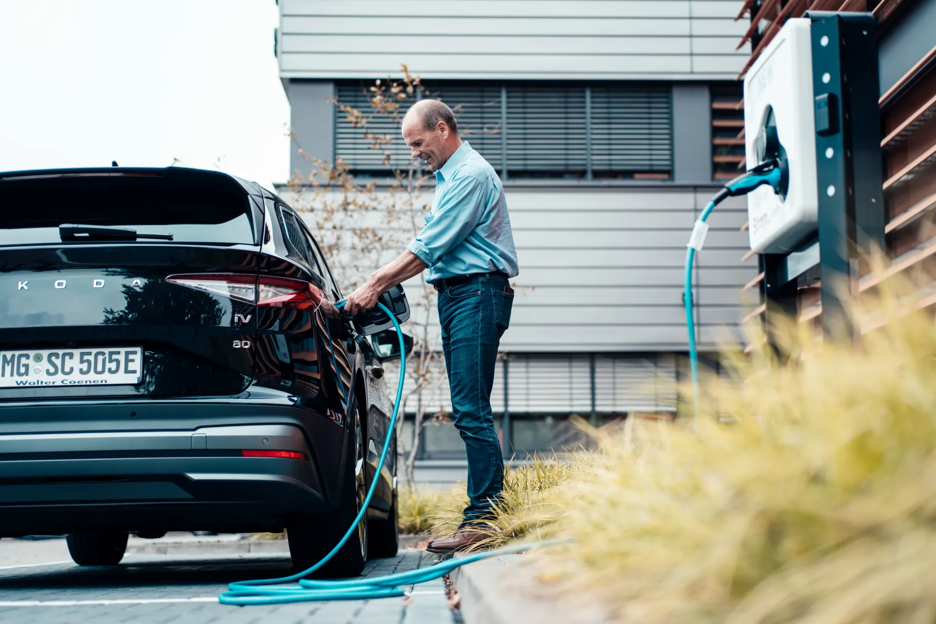 Ein Mann lädt sein E-Auto über die NEW Ladesäule auf.