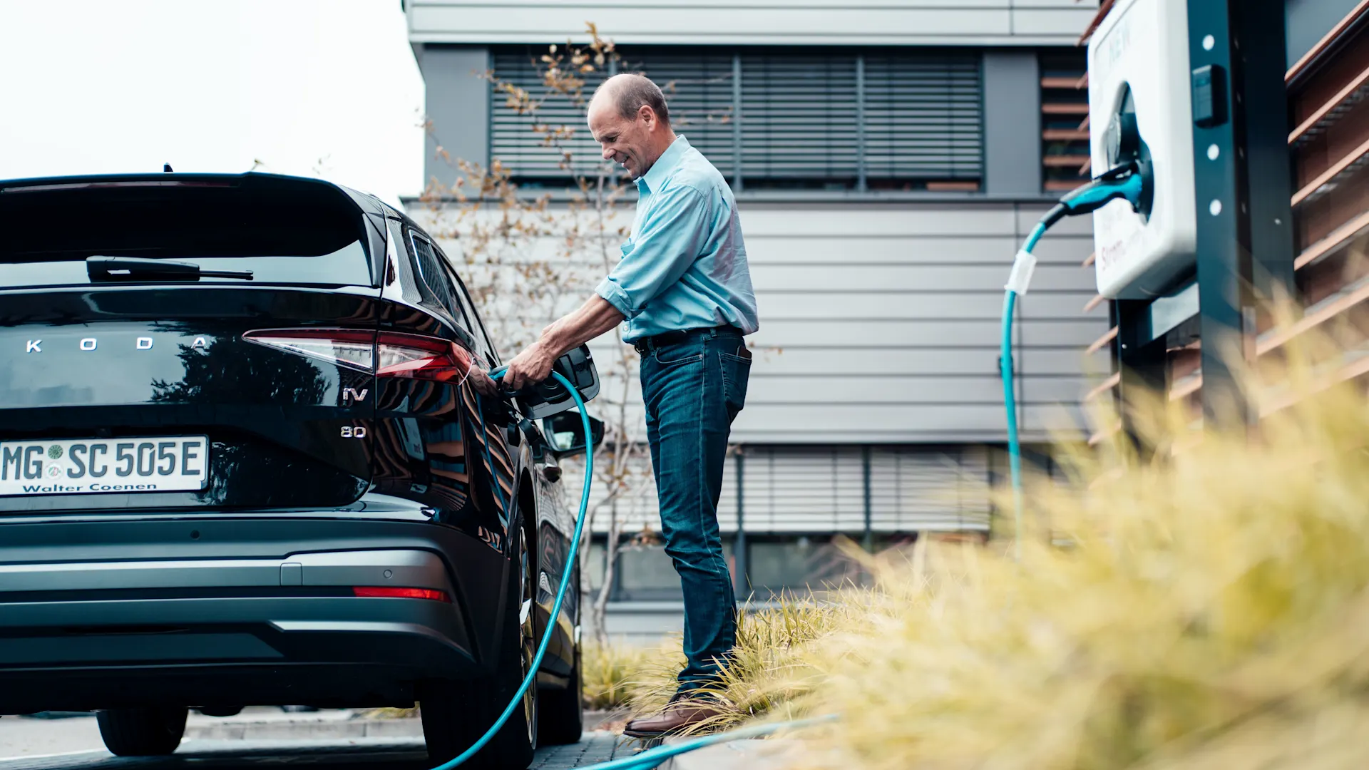 E-Auto über NEW Ladesäule laden Ein Geschäftsmann lädt sein E-Auto über die NEW Ladesäule auf.