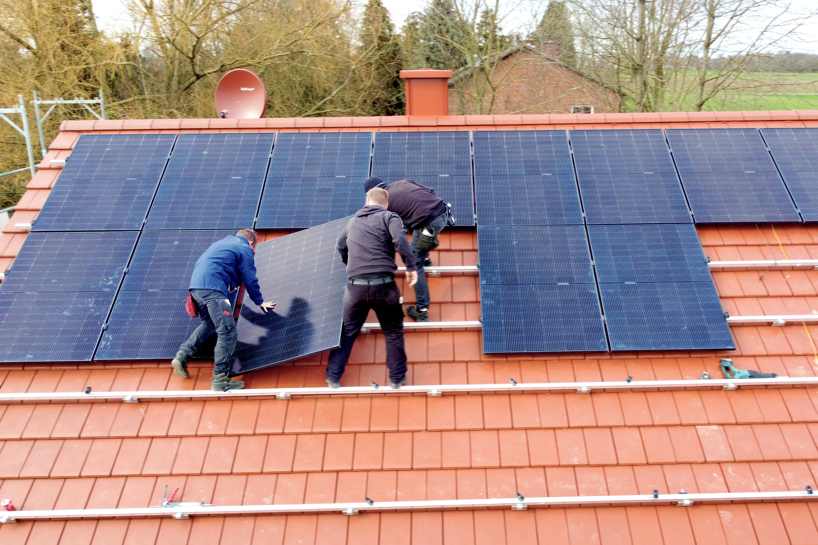 Mehrere Mitarbeiter der NEW montieren eine Photovoltaik-Anlage der NEW Energie auf einem Dach zur Herstellung von Ökostrom.