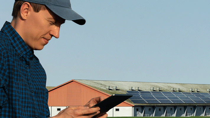 Ein Mann steht mit einem Tablet mit einigen PV-Anlagen der NEW Energie. 