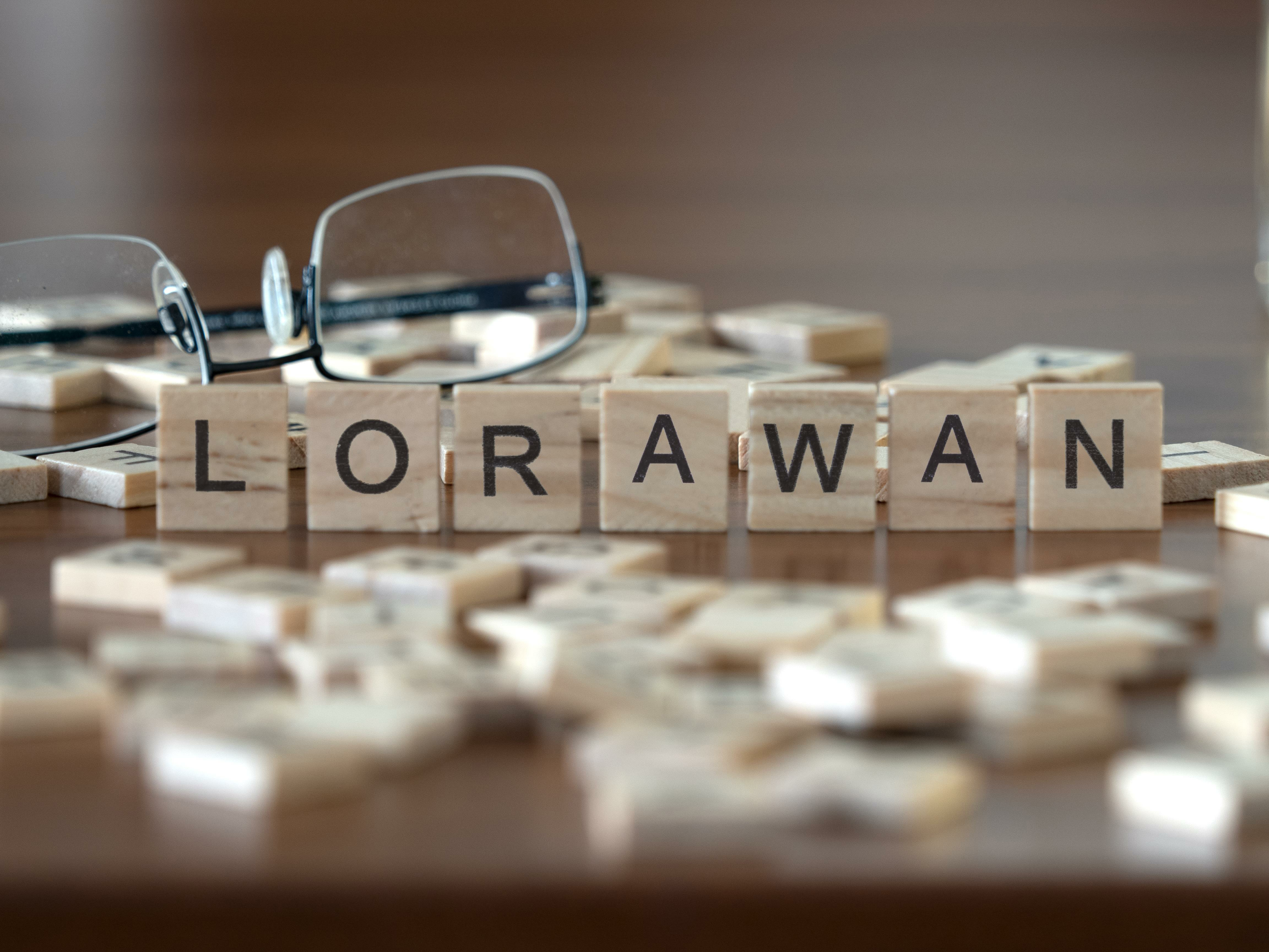 Auf einem Holztisch liegen Scrabble-Buchstaben, die das Wort „LoRaWAN“ bilden.