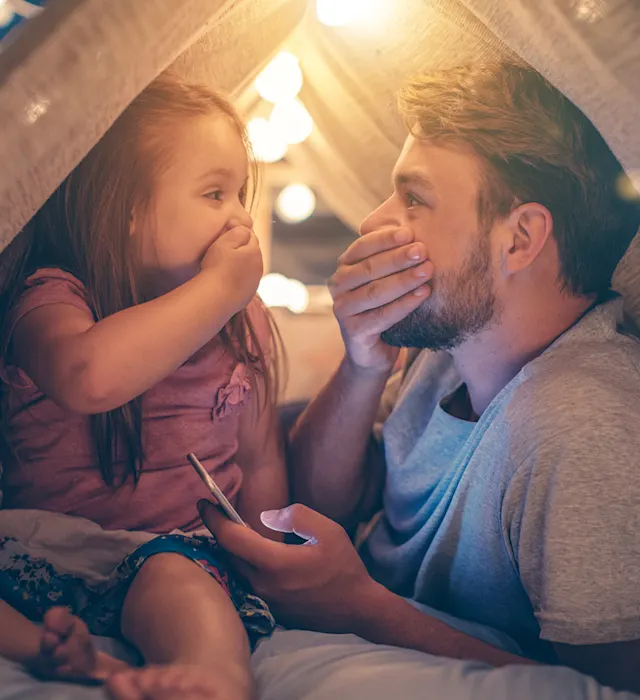 Vater und Tochter freuen sich über günstigen Strom Vater und Tochter sitzen im Wohnzimmer unter einer Deckenhöhle und freuen sich über günstigen Strom der NEW Energie.