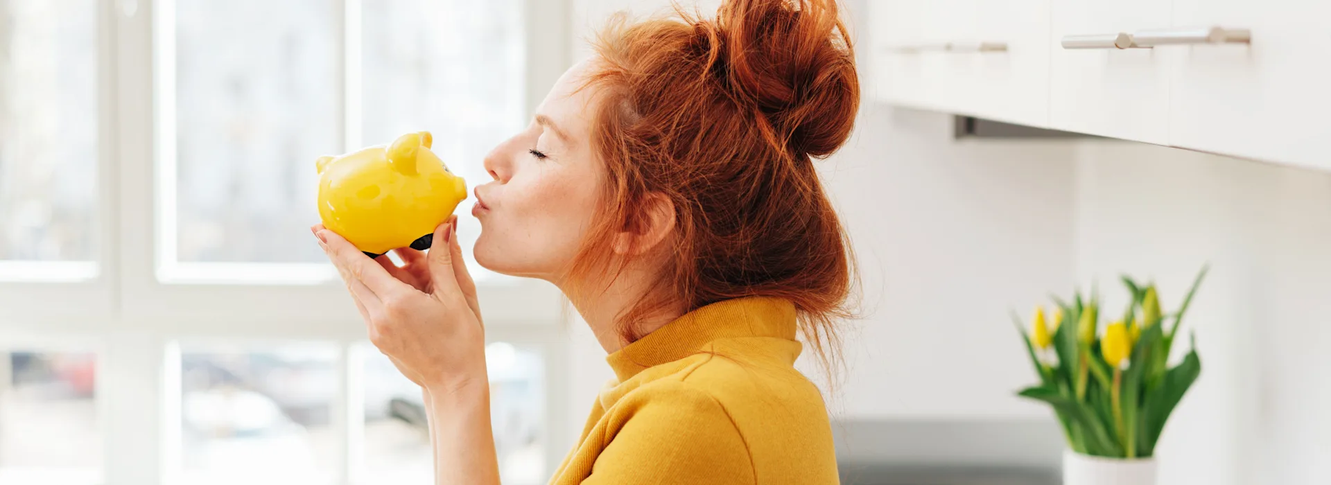 Freude am Sparen Die Frau küsst ihr Sparschwein als sie an das gute Angebot für ihren neuen Strom- und Gasvertrag bei der NEW Energie denkt.