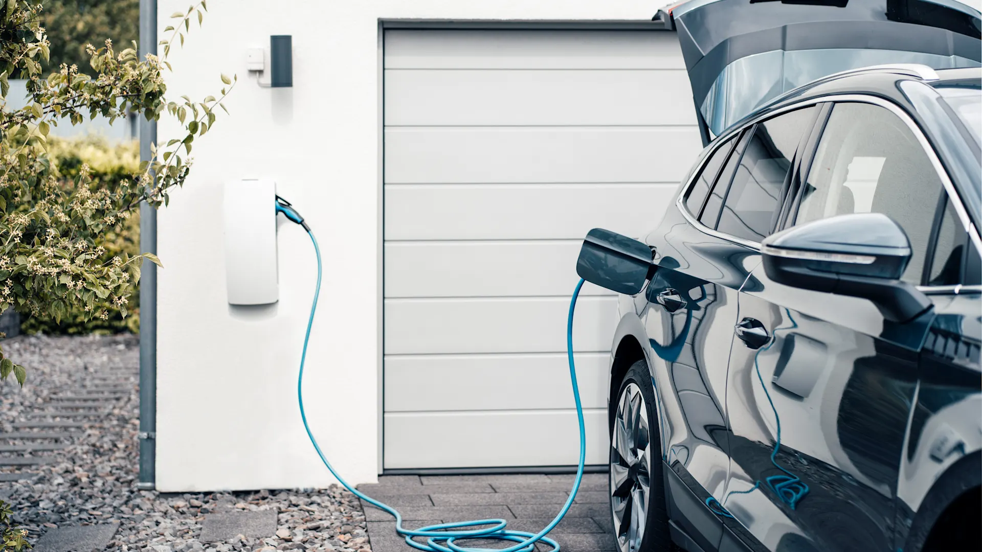 E-Laden bequem von Zuhause Ein Elektroauto ist an einem Haus an eine Ladestation angeschlossen.