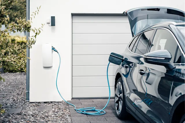 E-Laden bequem von Zuhause Ein Elektroauto ist an einem Haus an eine Ladestation angeschlossen.