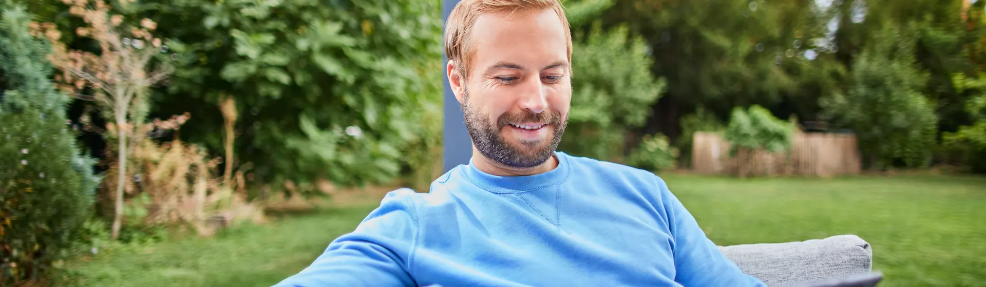 Ein Mann informiert sich über verschiedene Themen Ein Mann sitzt im Garten mit einem Tablet und informiert sich über die Tarife der NEW Energie.