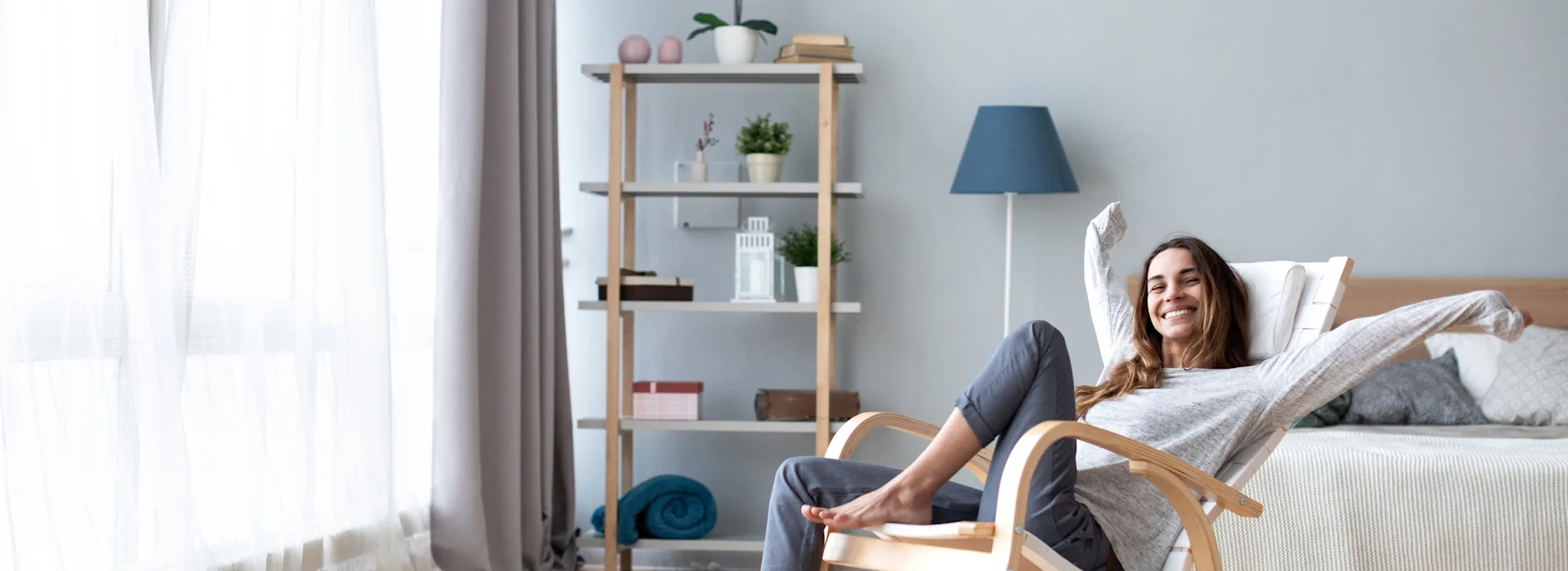 Frau lächelnd im Schaukelstuhl Die Frau sitzt lachend und entspannt im Schaukelstuhl in ihrem Wohnzimmer.