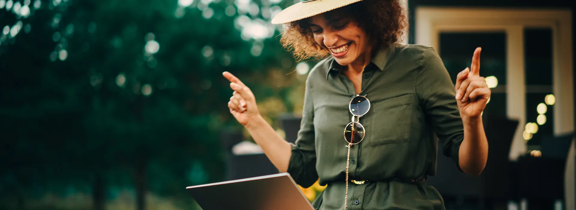 NEW Energie Sommeraktion mit 50 € Gutschein Eine Frau sitzt mit einem Laptop auf dem Schoß im Garten und freut sich über günstige Tarife der NEW Energie.
