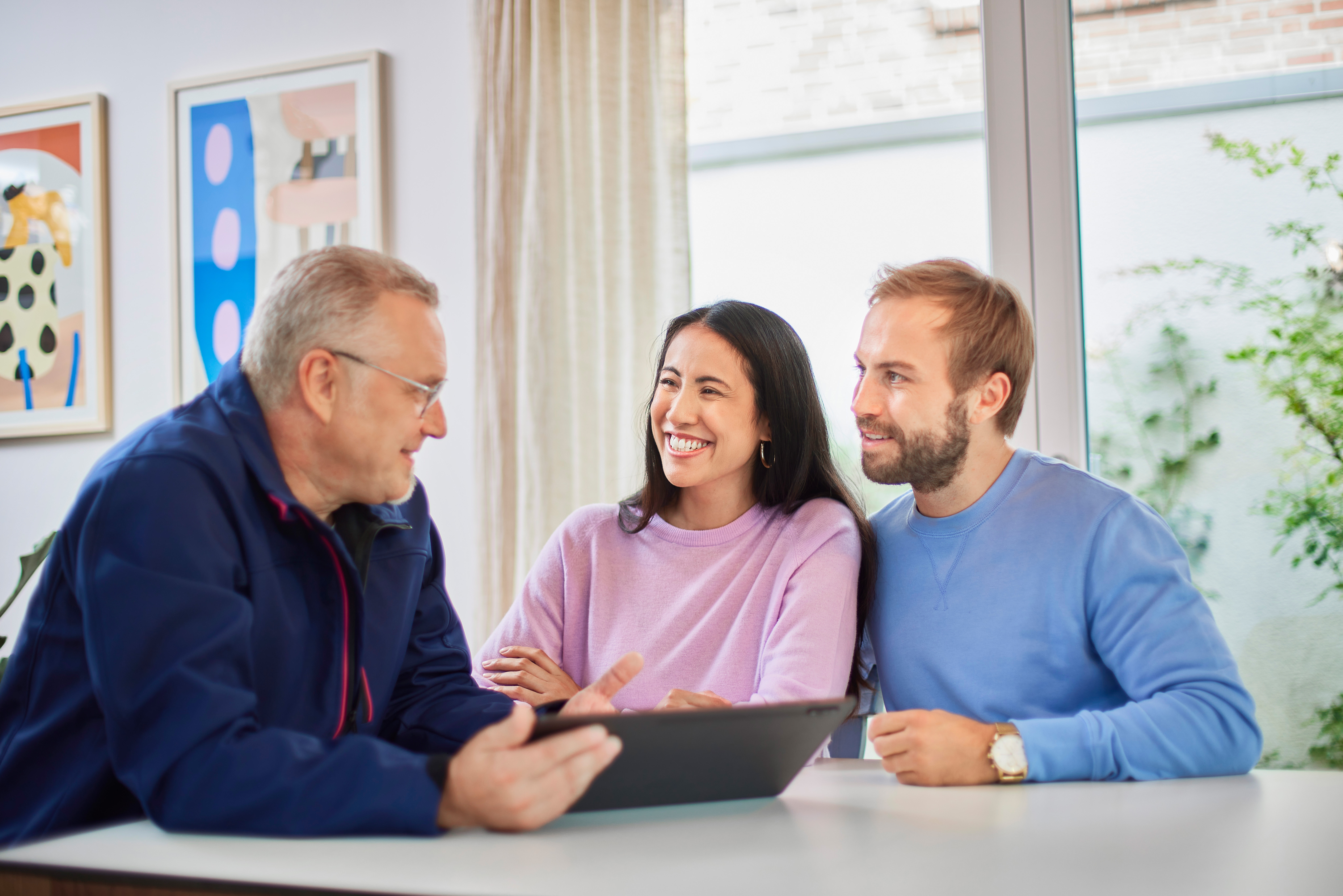 Ein Mitarbeiter der NEW leistet Beratungsservices bezüglich Energieeffizienz bei einem jungen Paar zu Hause.