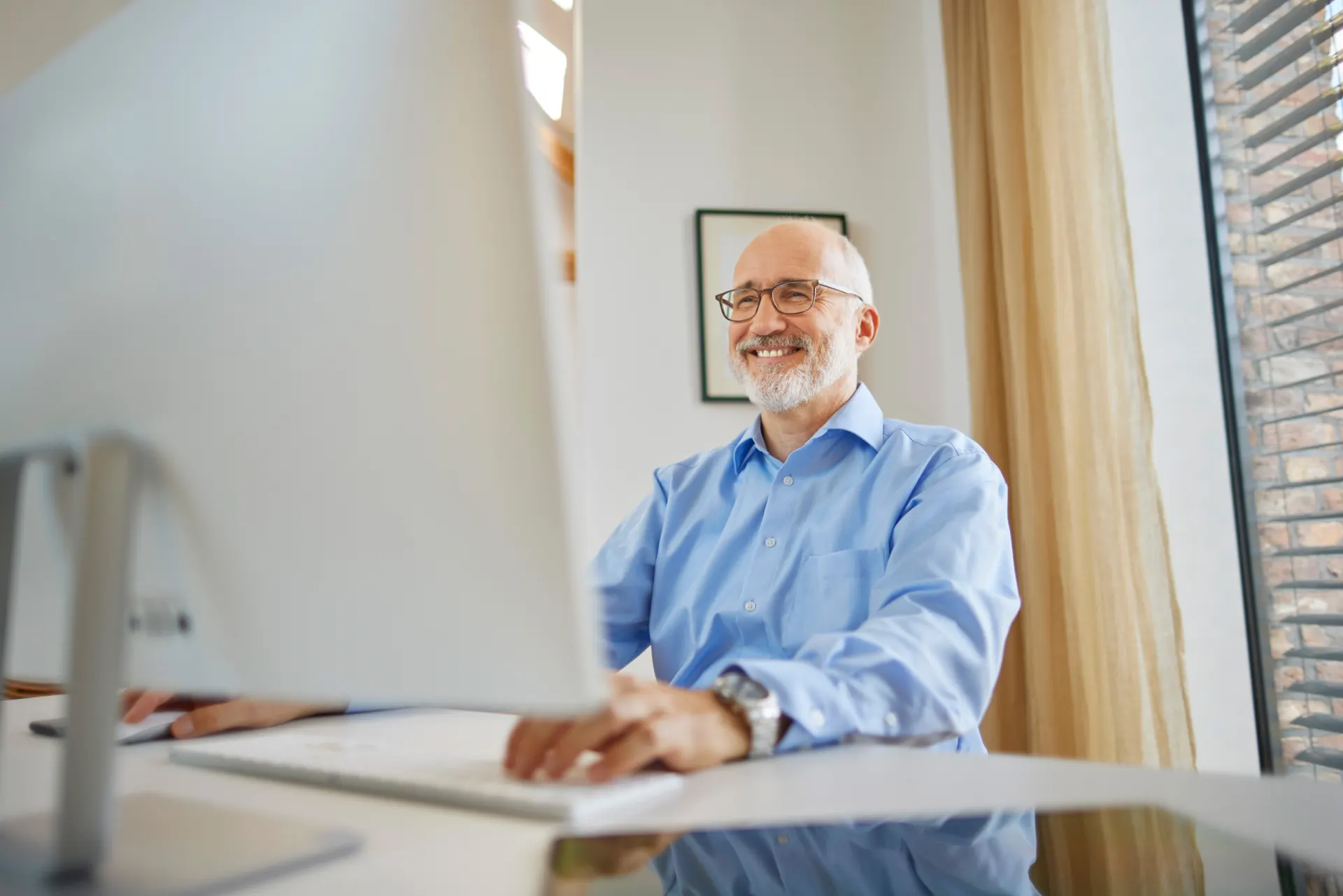 Ein Verwalter erfreut sich an der Arbeit am Laptop und bearbeitet sein Anliegen bei der NEW Energie.