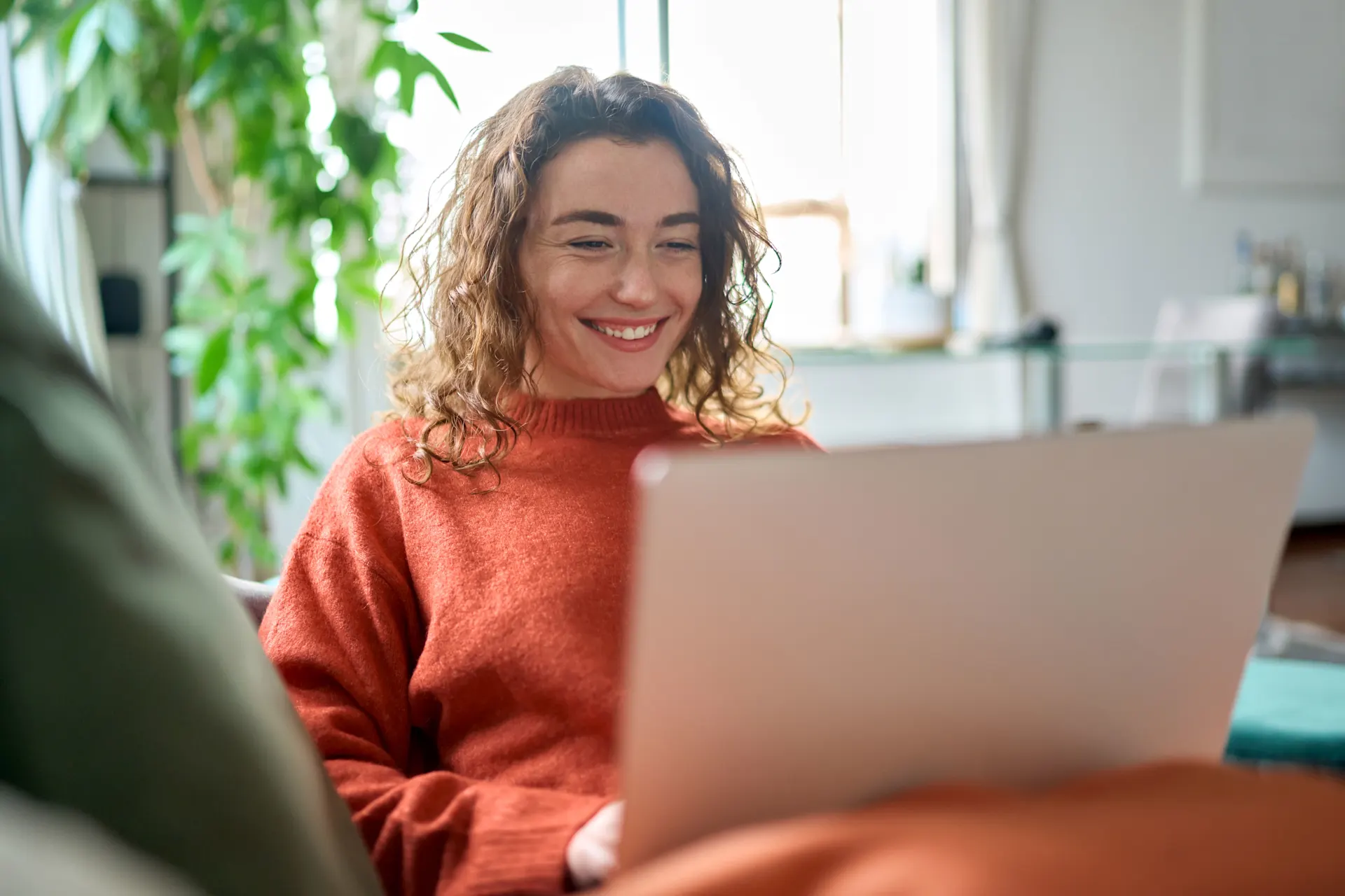 Studentin sitzt mit einem Laptop auf dem Sofa.