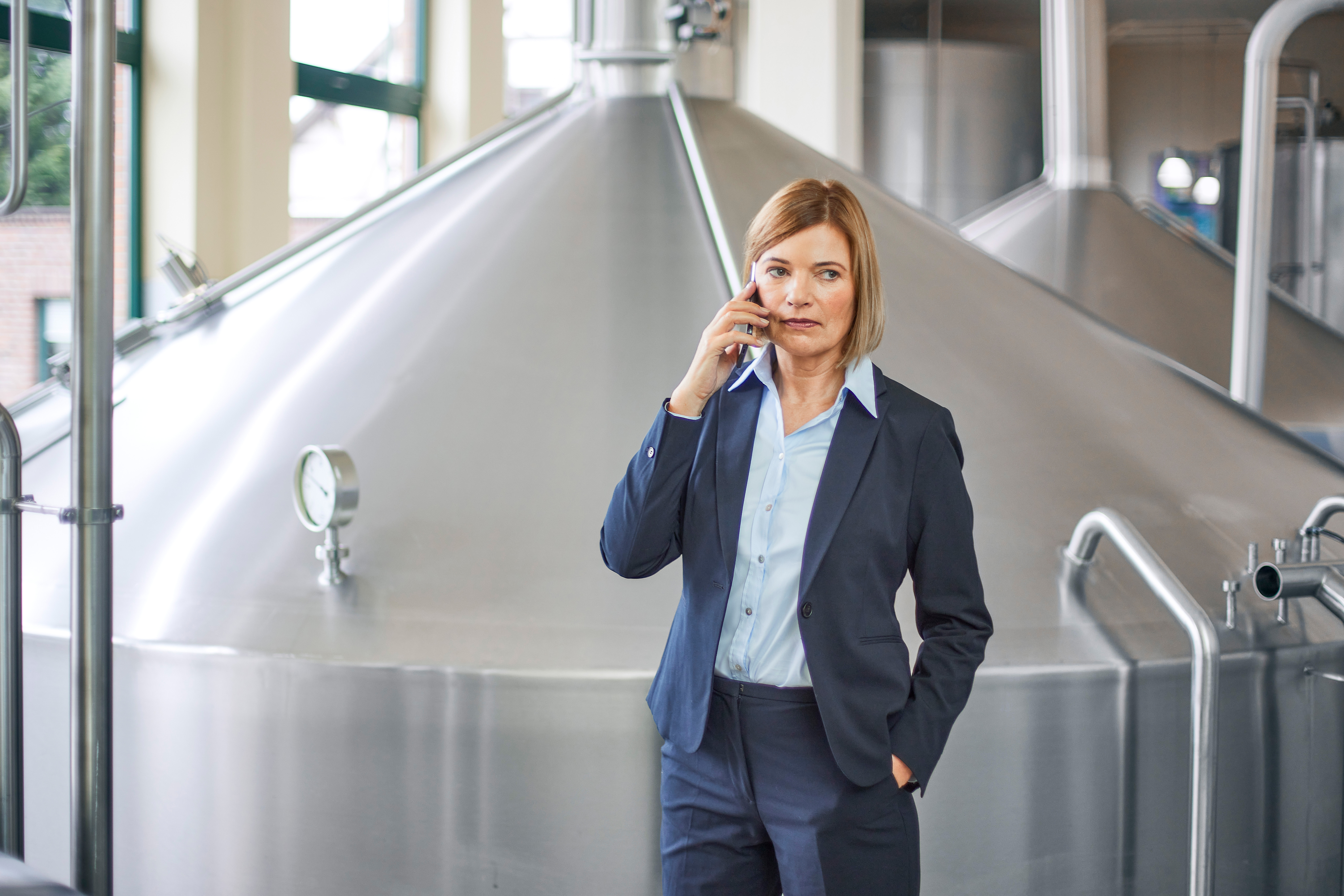Eine Geschäftsführerin führt ein Telefongespräch mit der NEW in einem Brauraum.