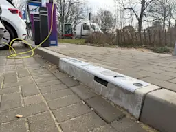 Ladebordstein bei der NEW Energie Auf dem Bild sieht man einen Ladebordstein der NEW Energie. Im Hintergrund steht eine Ladesäule der NEW.