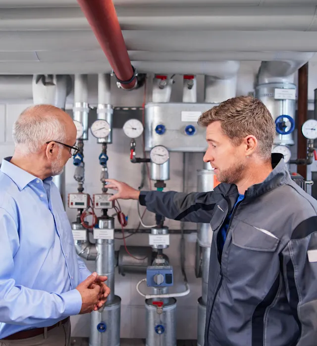 Beratung in einem Heizungsraum Ein Mann bekommt eine Beratung im Heizungsraum zur Heizungsanlage durch den Service.