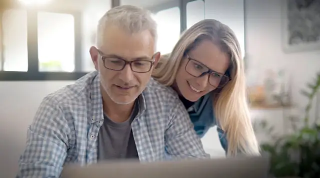 Pärchen informiert sich über die Services der NEW Energie Eine Frau schaut ihrem Mann über die Schulter. Er arbeitet am Laptop und besucht die Seite von der NEW Energie.