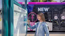Fahrplanänderungen Weiblicher Fahrgast die mit ihrem Handy an der Bushaltestelle Fahrplanänderungen prüft.