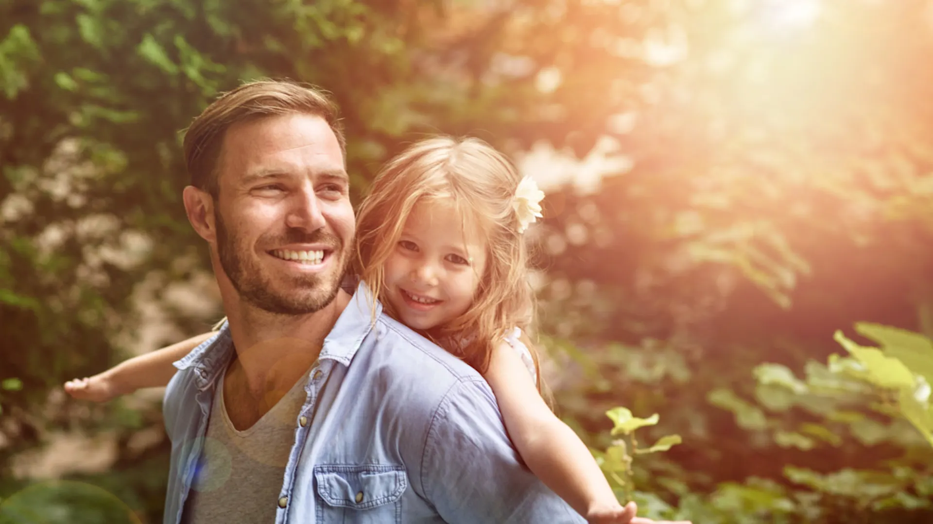 Smart City GmbH Vater mit Kind auf dem Rücken und Bäumen und Sonne im Hintergrund.