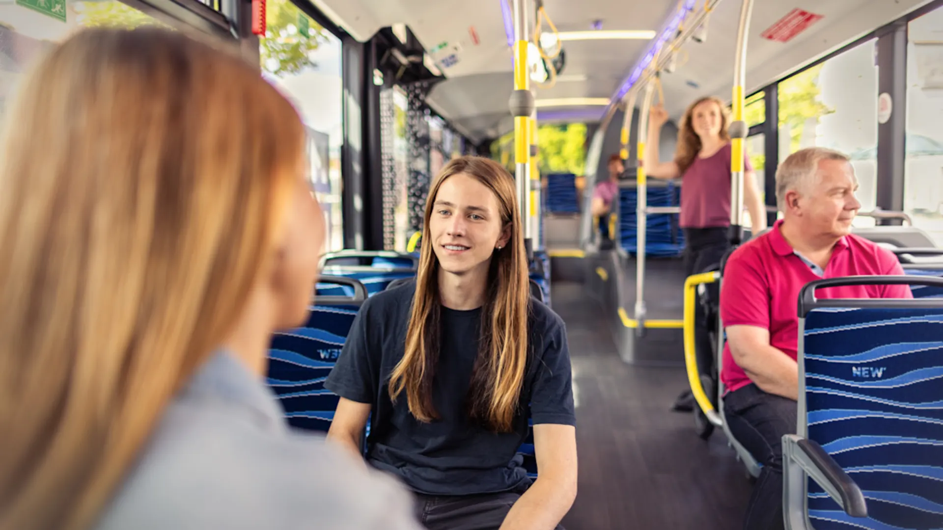 Vom Auto zum Bus: Warum sich der Umstieg lohnt Verschiedene Personen aller Altersgruppen sitzend in einem NEW Bus.
