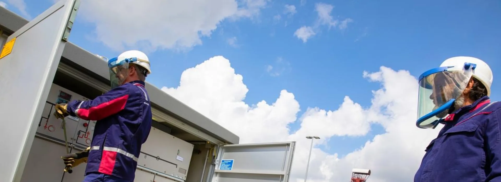 Mitarbeiter vor einer Trafostation Zwei Mitarbeiter der NEW Netz vor einer geöffneten Trafostation in Hückelhoven führen einen Schaltvorgang durch.