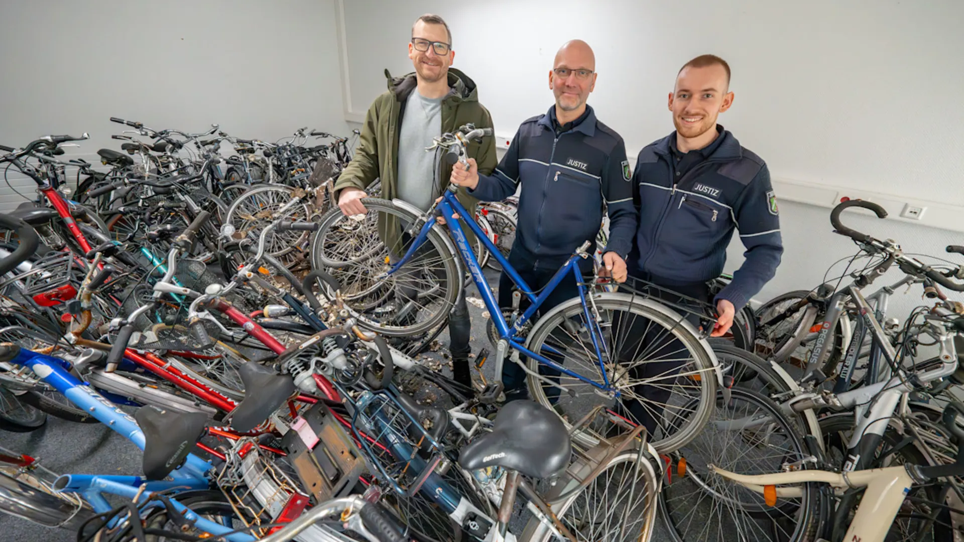 Pressebild NEW Velafrica Rund 50 alte Räder wurden an der Voltastraße von der NEW an Velafrica übergeben. Boris Theiner (Foto Mitte), Betriebsleiter in der JVA Aachen und sein Kollege Karsten Huppertz, nahmen die Fahrräder gerne von NEW-Mitarbeiter Lutz Löh entgegen.