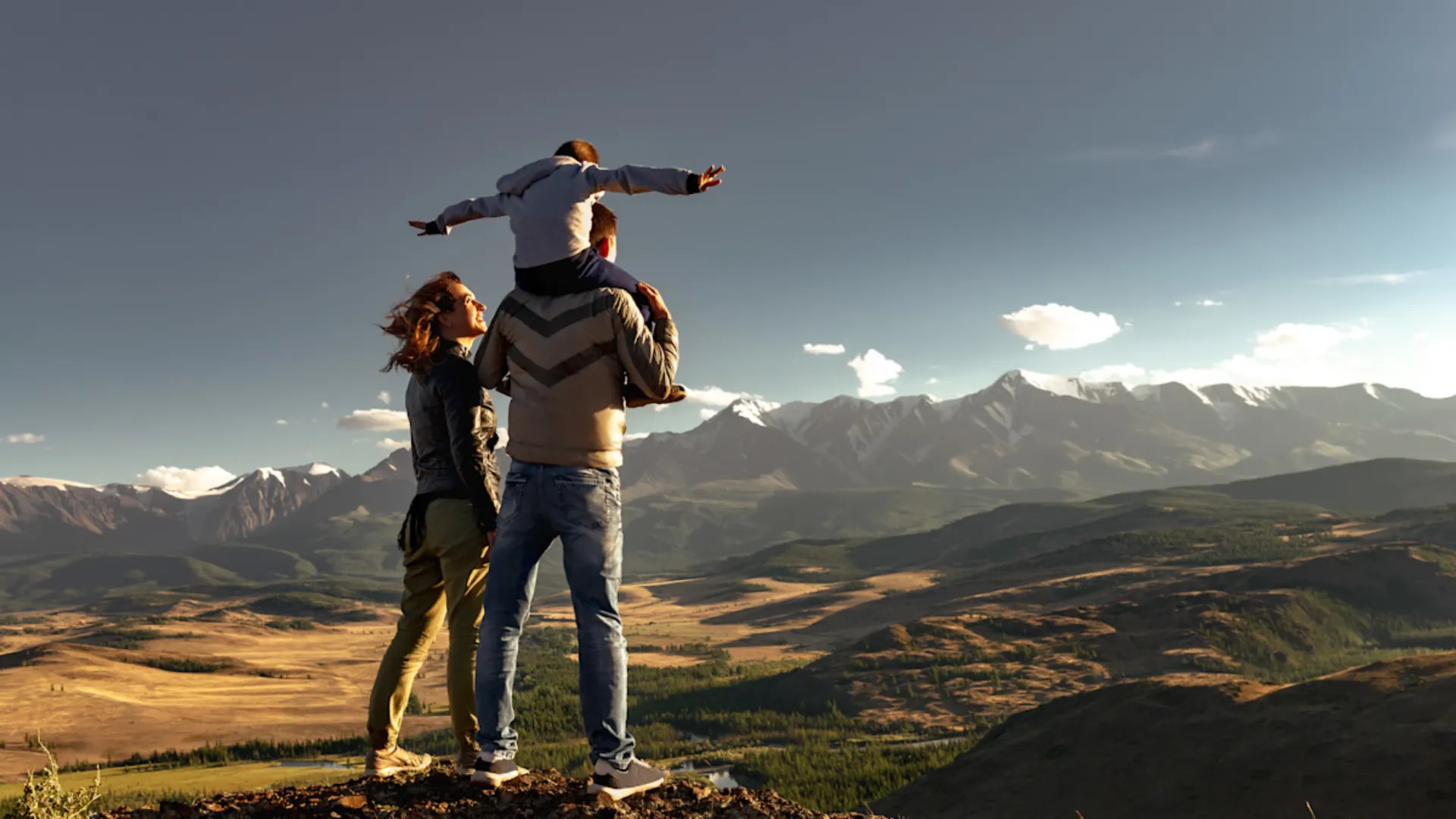 Smart City GmbH Eine Familie steht auf einer hügeligen Landschaft mit Blick auf ein paar Berge.