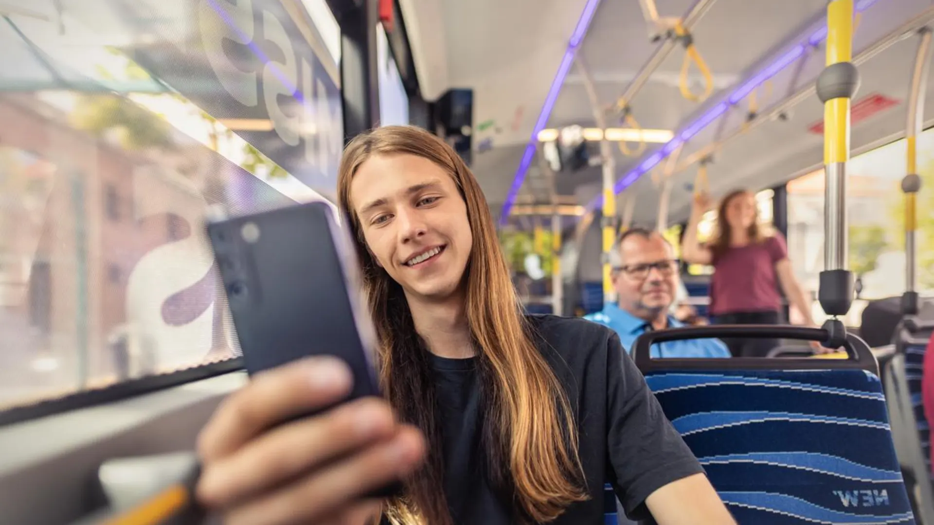 Fahrplanauskunft Junger Mann sitzt im Bus und schaut auf sein Smartphone.
