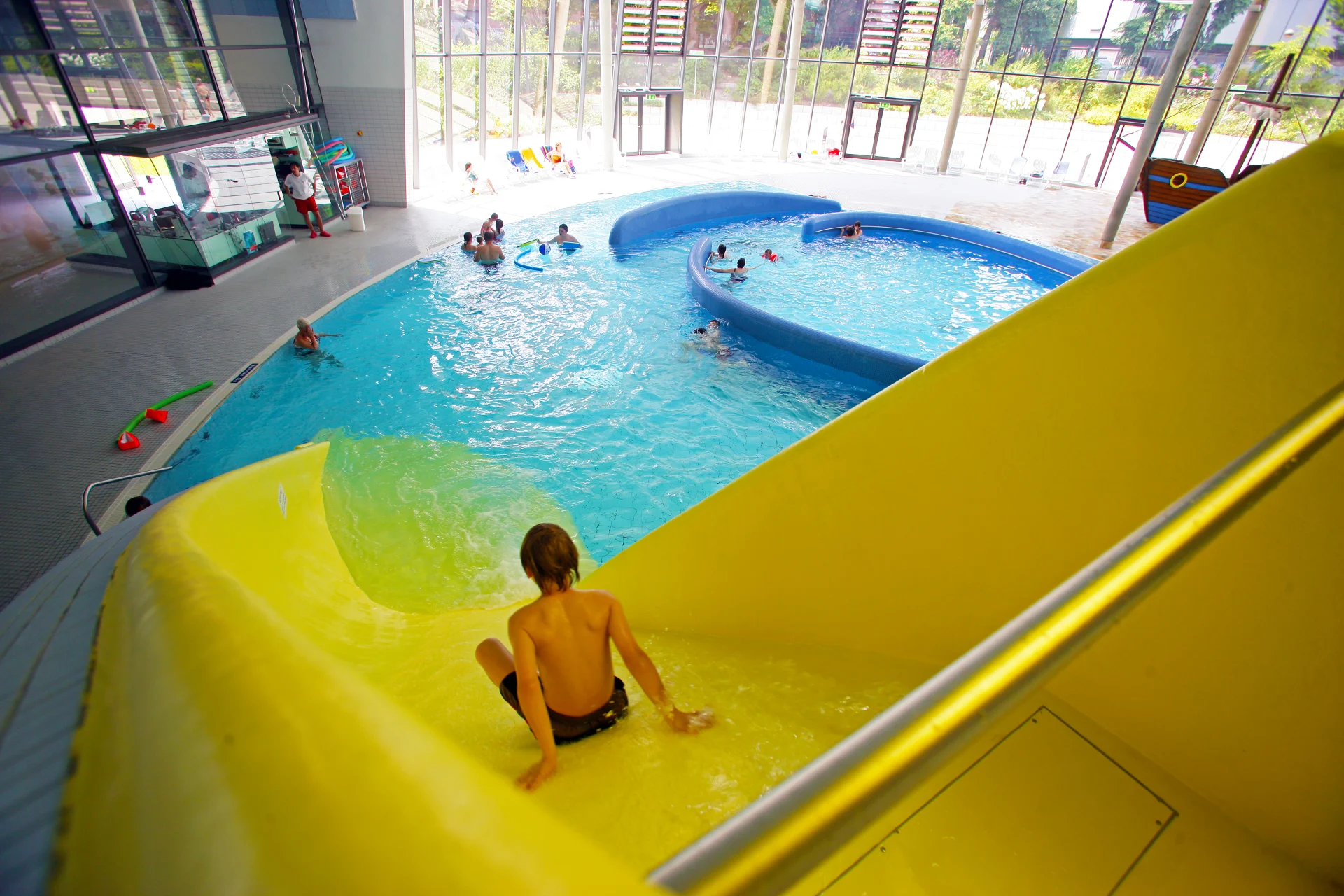 Schwimmspaß auf der großen Rutsche im vitusbad – ein Kind rutscht ins Wasser.