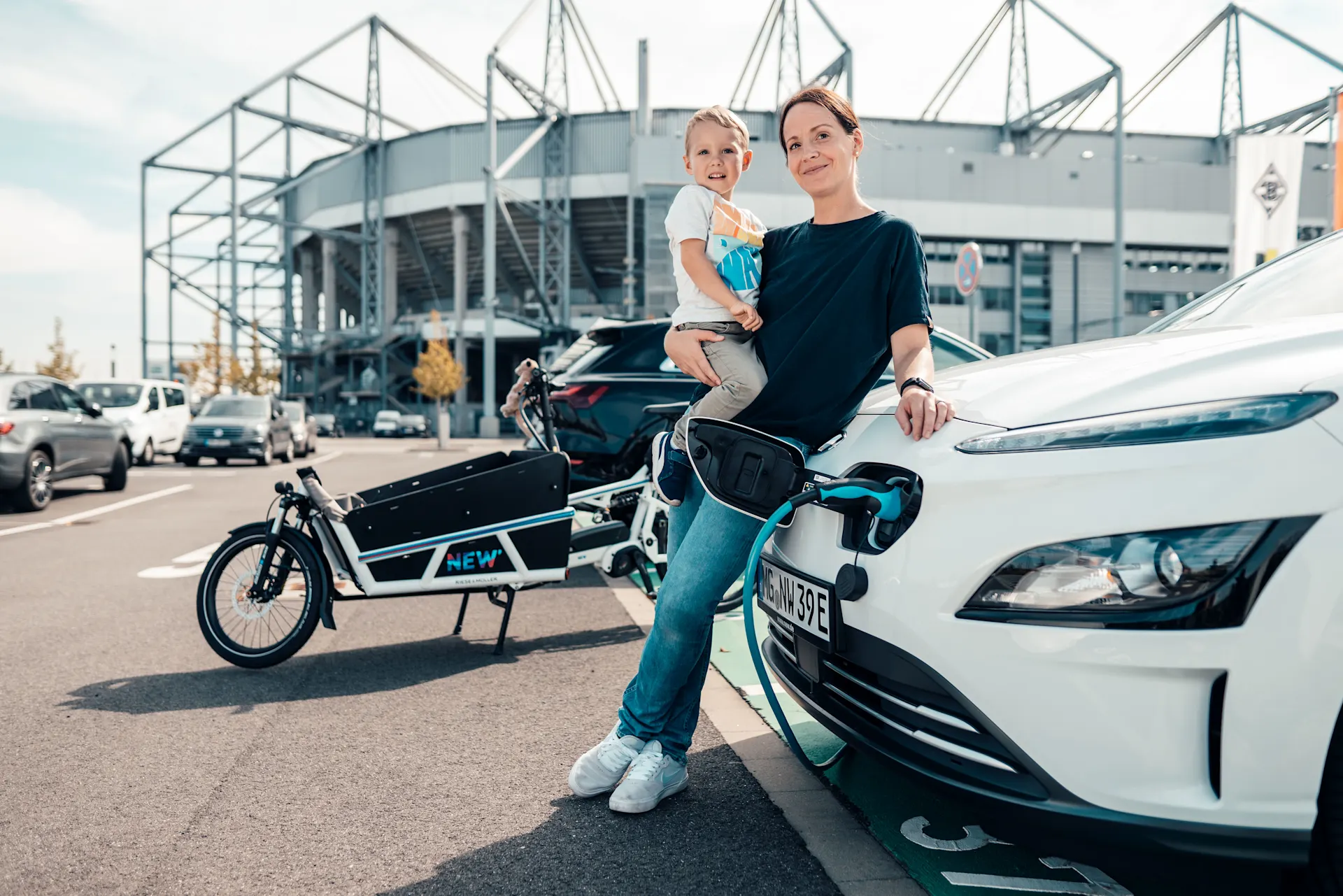 Mutter und Kind laden das E-Auto auf.