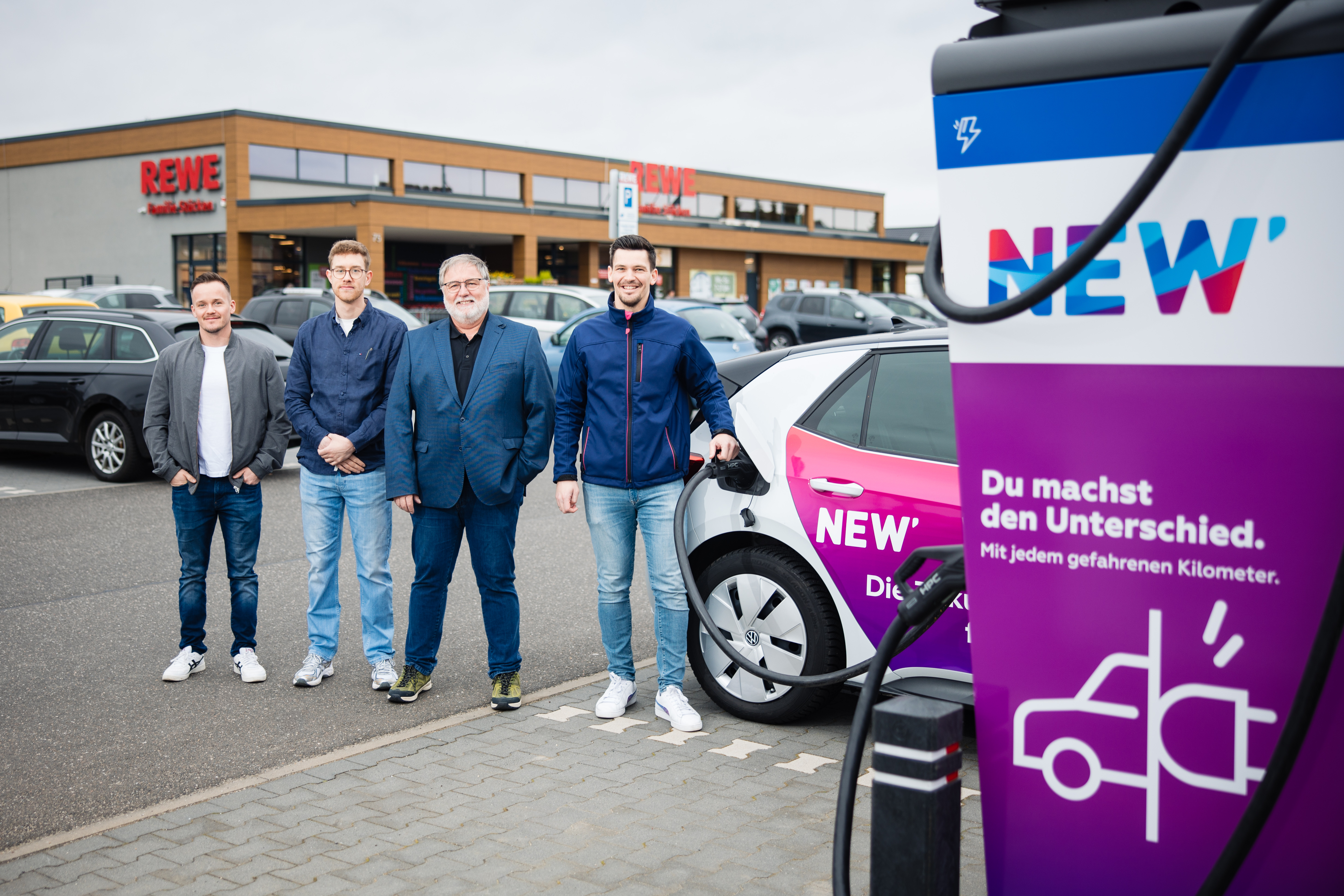Gemeinsam in eine elektrische Zukunft: NEW und REWE West machen mit neuen Schnellladesäulen auf dem Parkplatz des REWE Marktes der Familie Stücken in Niederkrüchten E-Mobilität in der Region am Niederrhein noch attraktiver: v.l.n.r. Frederic Hummelsiep (Vermietungsmanager, REWE Markt GmbH) Tom und Ralf Stücken (Geschäftsführer, REWE Stücken oHG), Johannes Vieten (Centerleiter Ladelösungen, NEW).