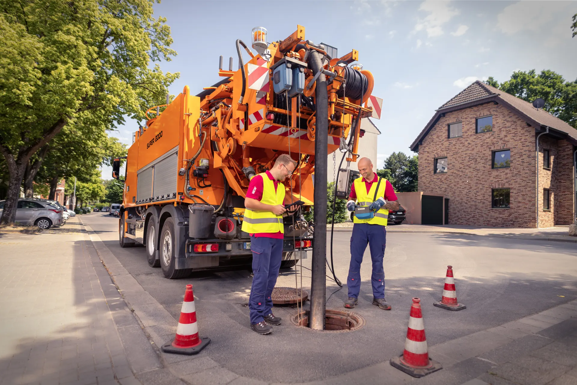 Saug- und Spülfahrzeug mit zwei Kollegen an einem Kanalschacht