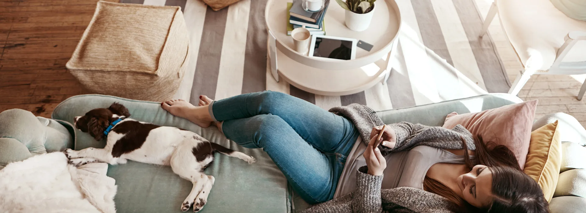 Frau schaut über ihr Smartphone nach Stromtarifen Eine Frau liegt im Wohnzimmer auf dem Sofa und schaut nach Stromtarifen der NEW Energie.