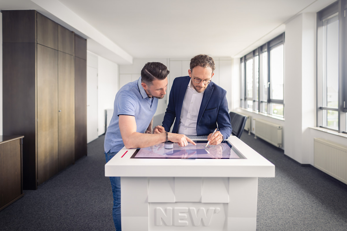 Zwei Kollegen vor einem digitalen Planungstisch
