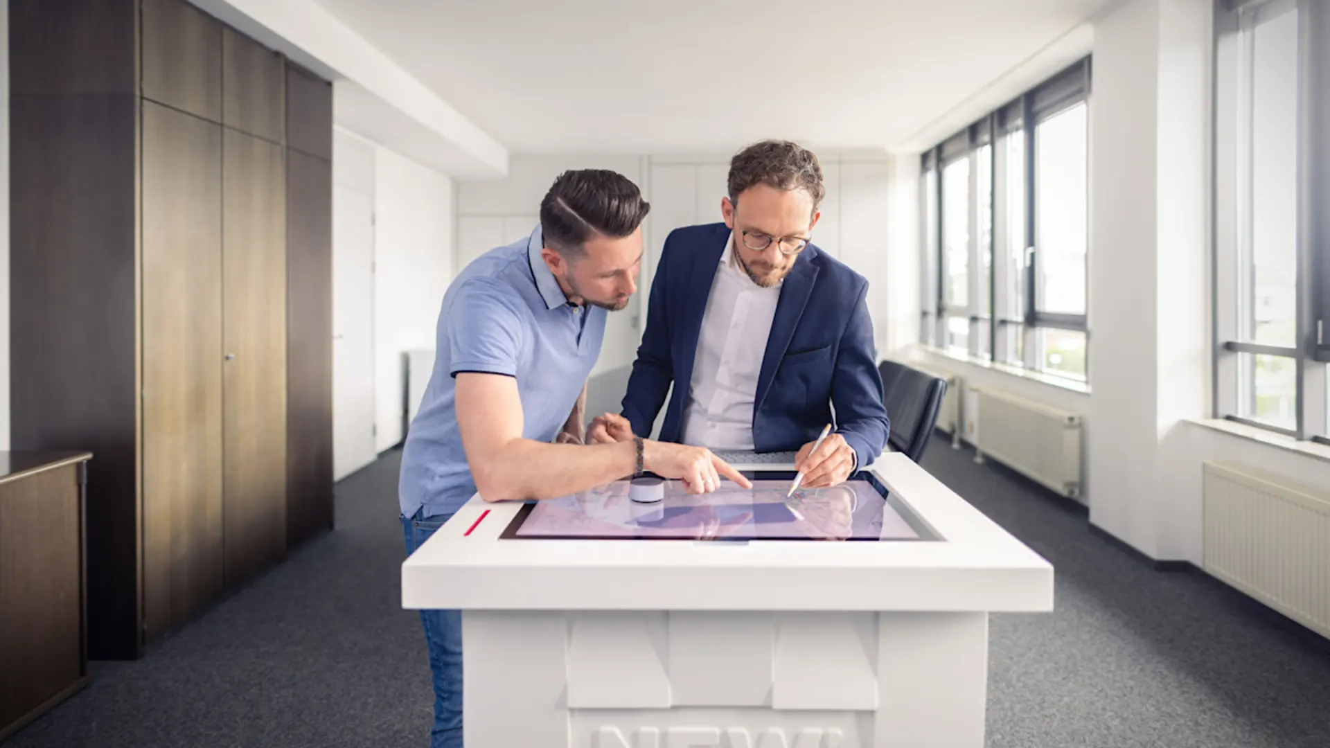 NEW-AG-digitalisierte-Prozesse-H8A3403 Zwei Kollegen vor einem digitalen Planungstisch